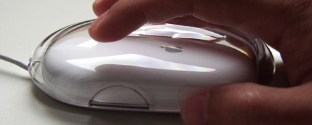 Photo of a hand gripping and manipulating an Apple brand mouse.
